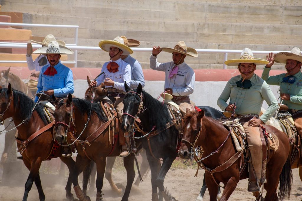 A group of Mexican charro cowboys in traditional attire riding horses in a rodeo arena, showcasing cultural heritage.